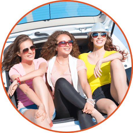 Three girls sitting on boot of car
