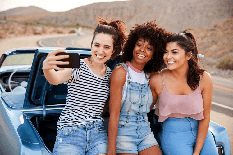 girls taking selfie by car